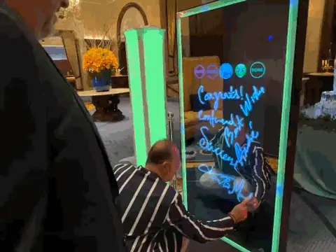 guests signing their photo on the mirror photo booth